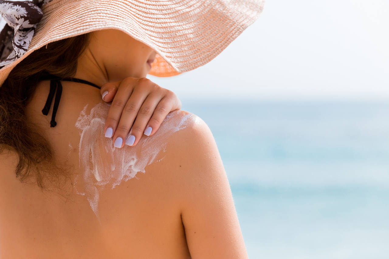 Mulher passando protetor solar no verão.